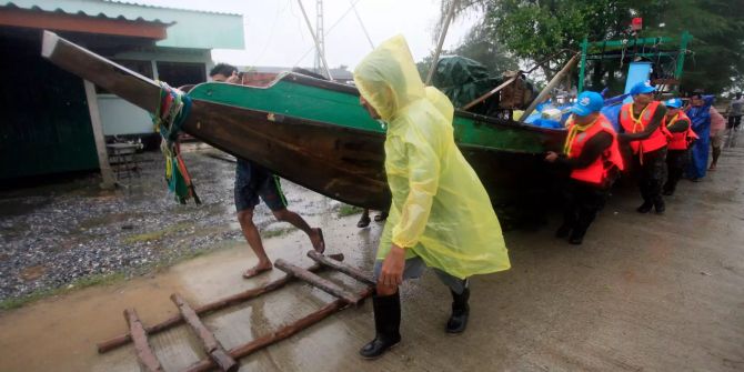 Menschen holen ein Boot in Thailand an Land.