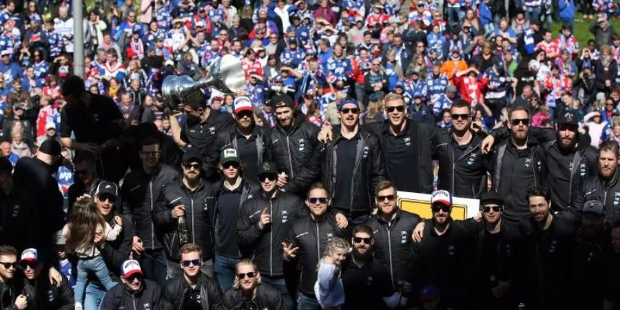 Teils mit dunklen Sonnenbrillen präsentiert die Mannschaft der Adler Mannheim den Fans den Meisterpokal. Foto: Michael Deines