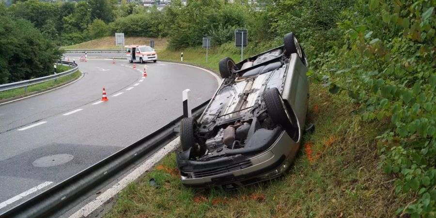 Ein Auto liegt in einer Wiese nahe der Autobahnausfahrt Gisikon LU auf dem Dach.