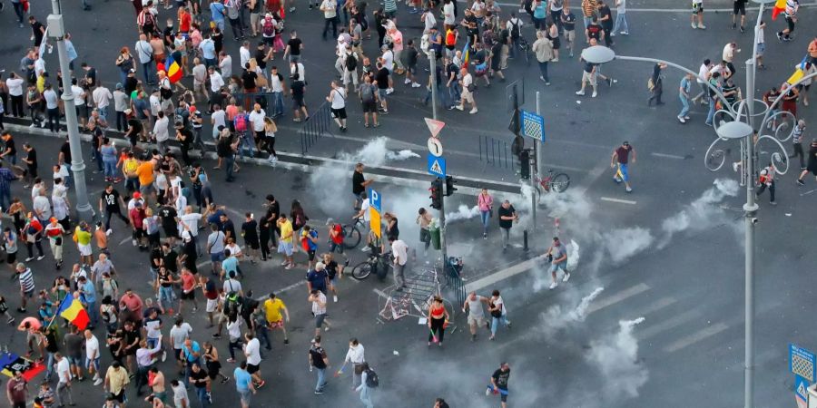 Demonstranten gehen zwischen Tränengaskanister umher. Im Ausland lebende Rumänen haben zu Protesten gegen die Regierung aufgerufen, weil sie mit ihr unzufrieden sind. Einige Auswanderer kamen aus ganz Europa, um an den Protesten teilzunehmen.