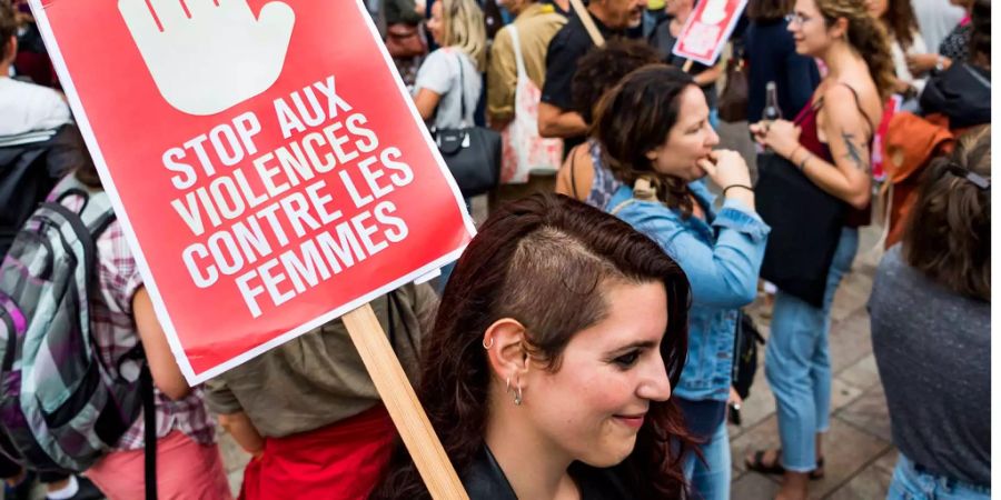 Eine Frau an der Demonstration in Genf gegen Gewalt an Frauen. Auf dem Schild steht: Stoppt die Gewalt gegen Frauen.