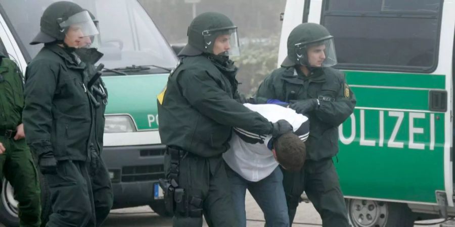 Deutsche Polizisten führen einen Fussball-Hooligan ab.