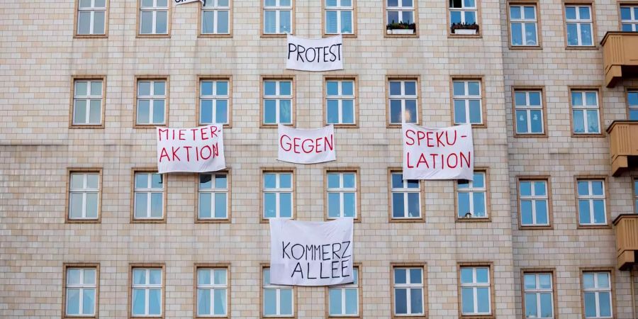 Plakate gegen den Verkauf von Mietwohnungen an die Deutsche Wohnen SE hängen an einer Gebäudefassade in der Karl-Marx-Allee.