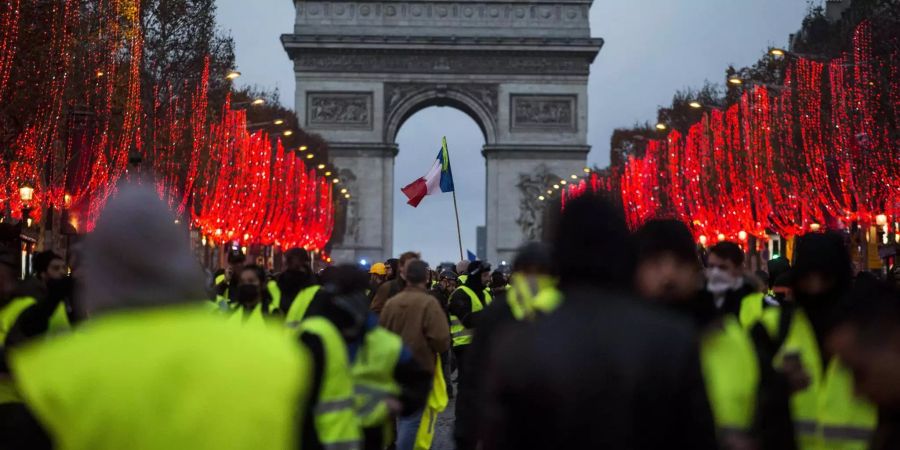 Demonstranten stehen vor dem Arc de Triomphe.