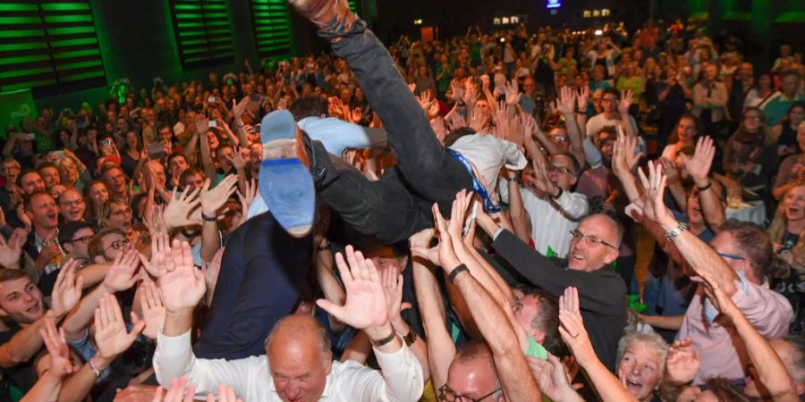 Der Bundesvorsitzende Robert Habeck (r) und der bayerische Spitzenkandidat von Bündnis 90/Die Grünen, Ludwig Hartmann springen bei der Wahlparty der Partei von der Bühne ins Publikum.