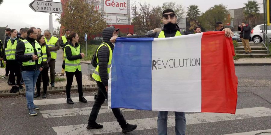 Ein Demonstrant hält eine französische Flagge mit der Aufschrift «Revolution».