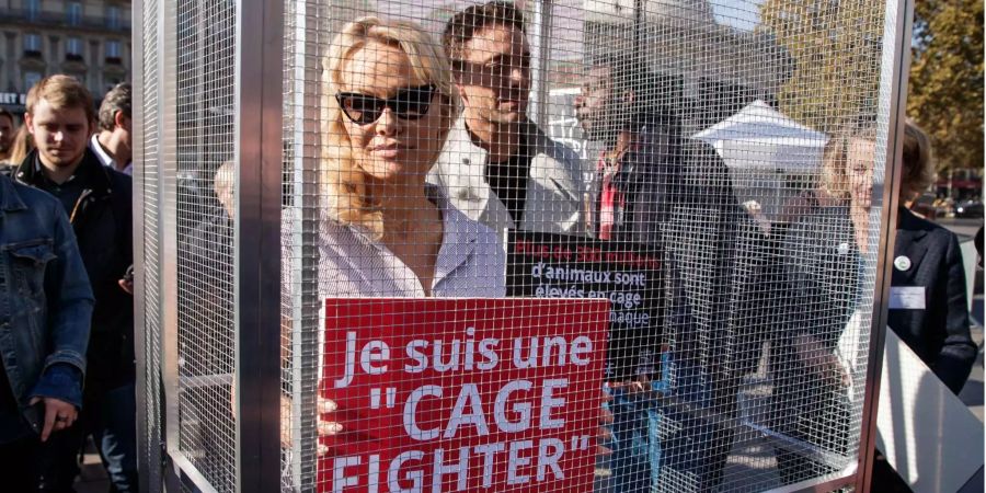 Die Schauspielerin Pamela Anderson (l..) und ihr Tanzpartner bei «Danse avec le stars» Maxime Deremez (r.) halten bei einer Demonstration in Paris gegen Käfighaltung ein Schild hoch auf dem steht: «Ich bin eine Käfigkämpferin».