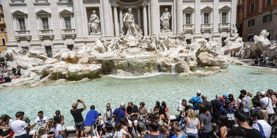 Der Trevi-Brunnen in Rom zieht zahlreiche Touristen an, die Fotos schiessen, und manchmal sogar darin baden.