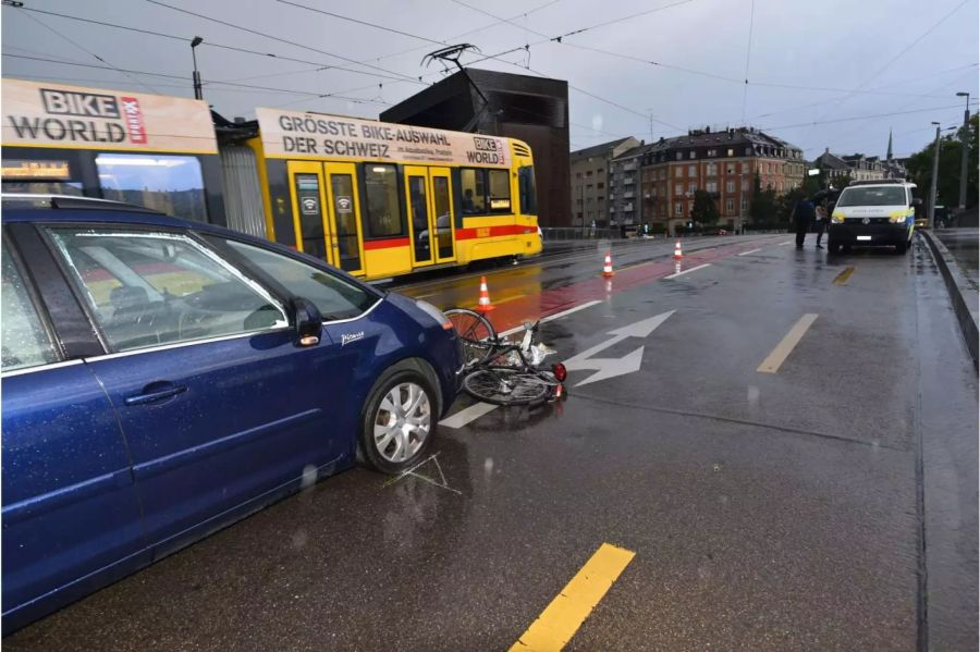 Verunfalltes schwarzes Fahrrad vor einem blauen Auto am Boden - zvg Kantonspolizei Basel-Stadt