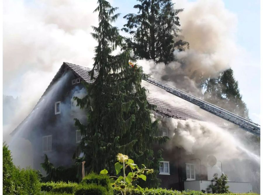 Aus Dachstock drängt viel Rauch und Feuerwehrleute bekämpfen das Feuer von einer Leiter aus - zvg Luzerner Polizei