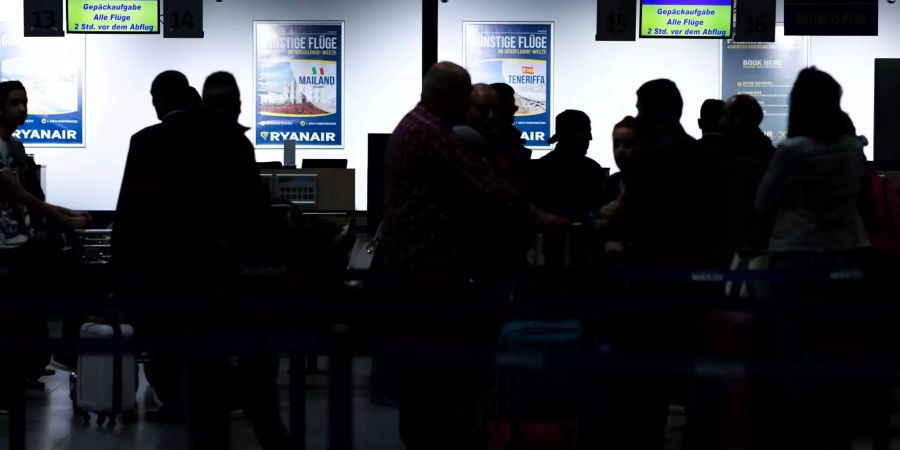 Fluggäste warten vor dem Check-In-Schalter der irischen Airline Ryanair im Flughafen Weeze (D).