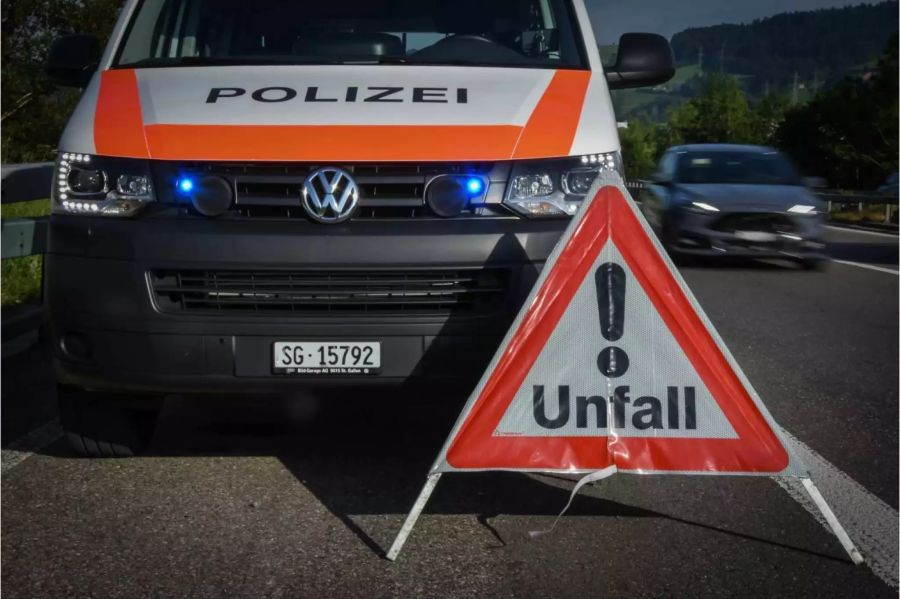 Unfall Warndreieck auf der Strasse und daneben ein Polizeiwagen - Keystone