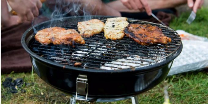 Zwei Personen grillen im Grünen. Grillen Park