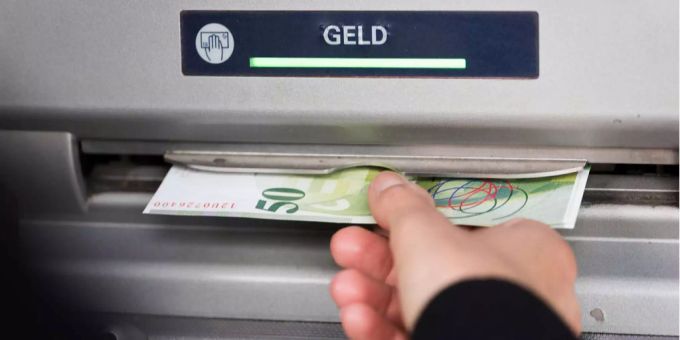Eine Person nimmt eine Schweizer Geldnote aus dem Bankautomaten. Eine Person nimmt eine Schweizer Geldnote aus dem Bankautomaten.