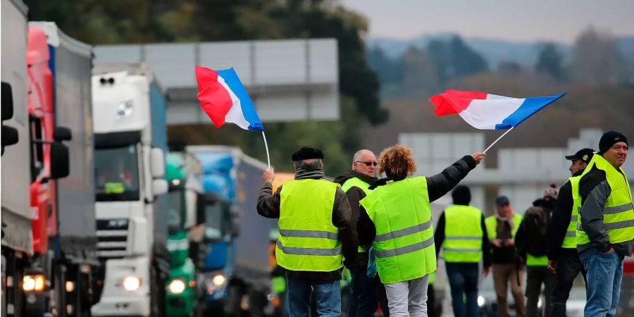 Demonstranten schwenken französische Flaggen, während sie Lastwagen auf der Autobahn blockieren. Es ist nun das dritte Wochenende in Folge, an dem die Protestgruppe mit Grossaktionen landesweit demonstriert.