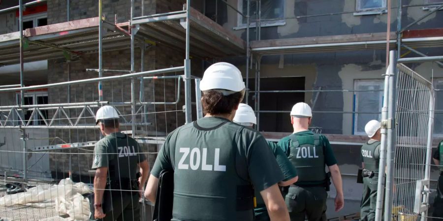 Deutsche Zollbeamte betreten bei einer Razzia gegen Schwarzarbeit eine Baustelle.