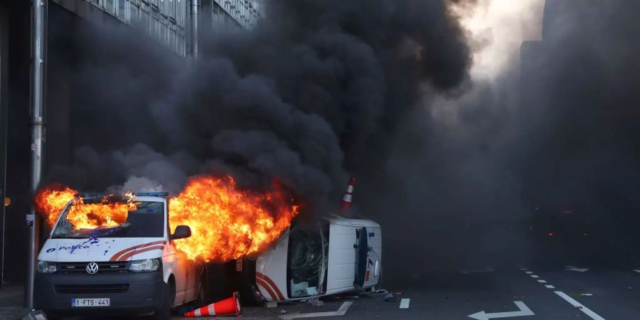Ein brennender und ein beschädigter Polizeiwagen stehen bei einem Protest der sogenannten «Gelbwesten» gegen steigende Spritpreise auf einer Strasse in Brüssel.