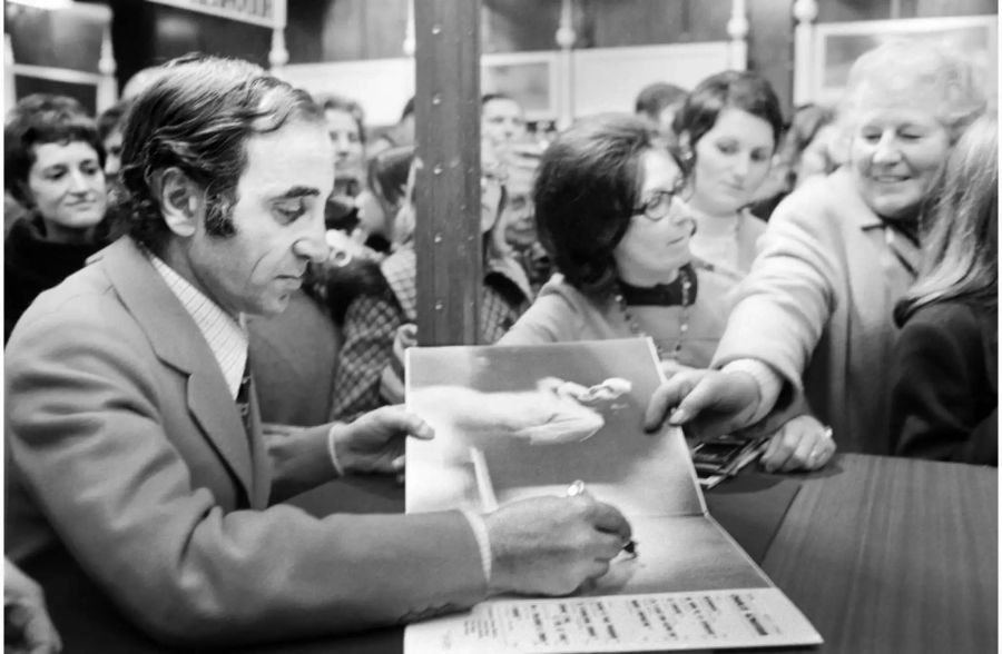 Der französische Chansonnier und Schriftsteller Charles Aznavour signiert am 18. Februar 1971 in Genf, Schweiz, sein Buch "Aznavour par Aznavour".