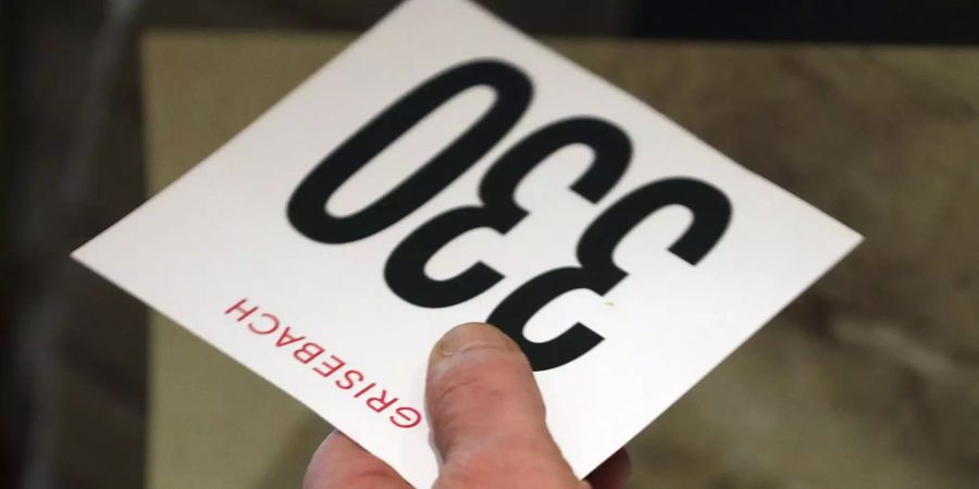 Ein Interessent hält eine Karte mit seiner Bieternummer bei einer Versteigerung in der Hand.
