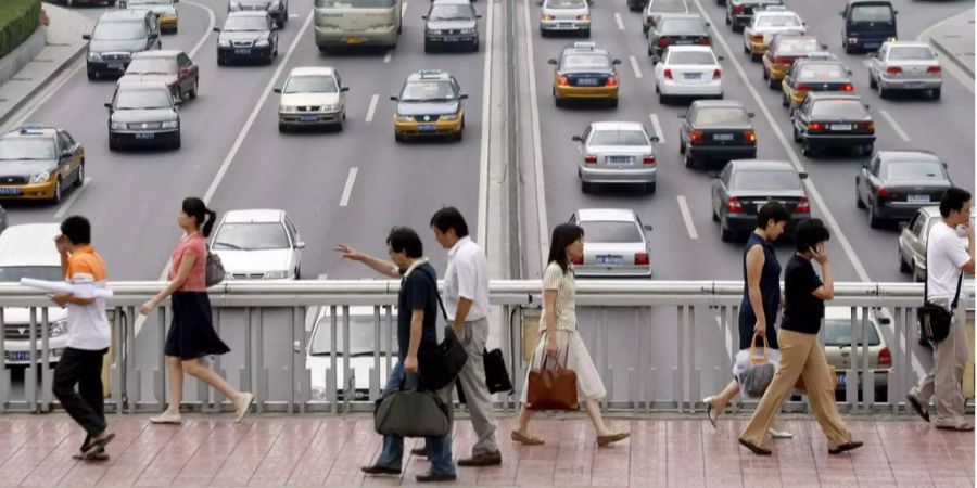 Passanten laufen auf einer Brücke in Peking.