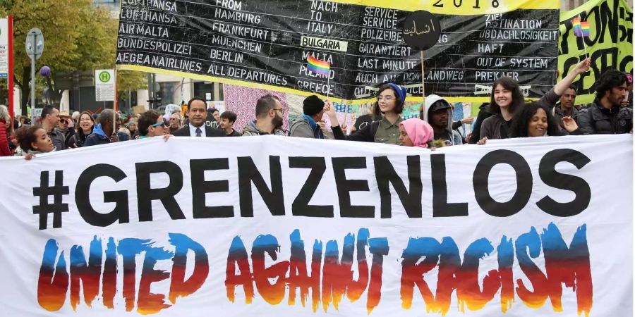 Mit Schildern und einem Transparent mit der Aufschrift "Grenzenlos - United against Racism" ziehen Teilnehmer bei einer bunten Parade gegen Rassismus durch Hamburg.