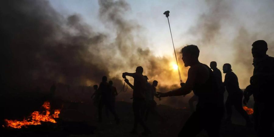 Palästinensische Demonstranten schleudern Steine in Richtung israelischer Truppen während eines Protests im Gazastreifen.