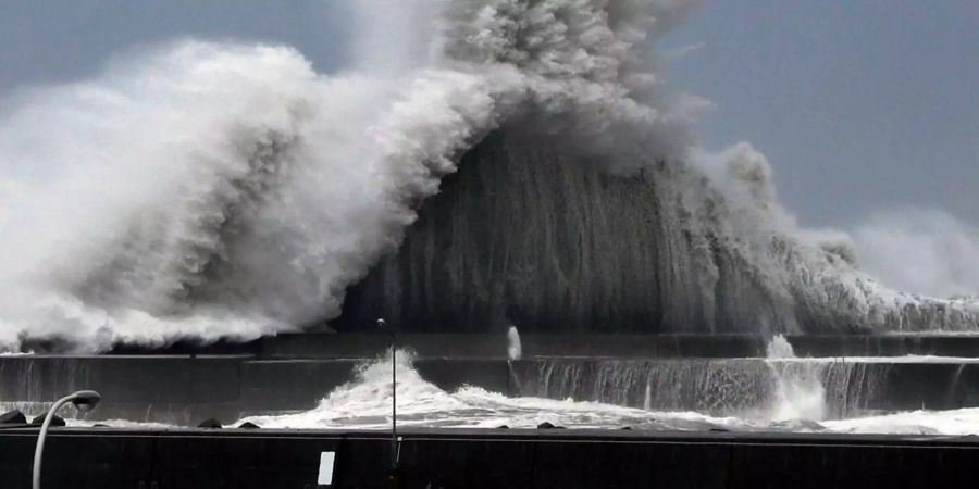 Hohe Wellen brechen an Wellenbrechern in einem Hafen von Aki (Japan).