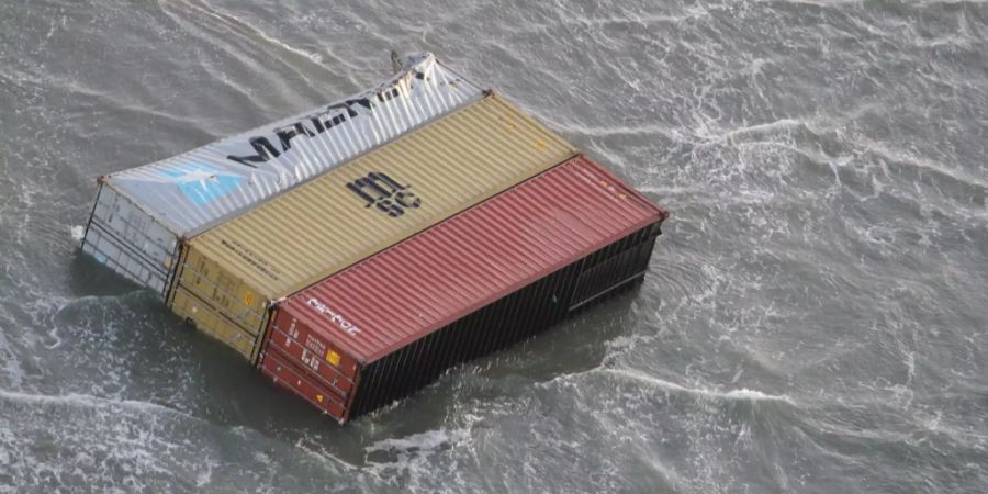 Mehrere Container liegen am Strand.