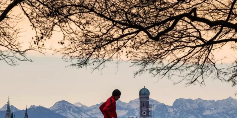 Der Winter zieht sich in die Berge zurück: Hinter der Skyline von München ist das leicht verschneite Alpenpanorama zu erkennen. Foto: Peter Kneffel/dpa