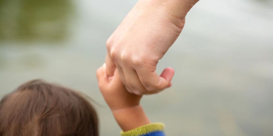 Eine Mutter hält ihr Kind an der Hand.