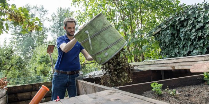 Viele Küchen- und die Grünabfälle aus dem Garten werden auf einem Kompost mit der Zeit zu Dünger. Mann am Komposthaufen