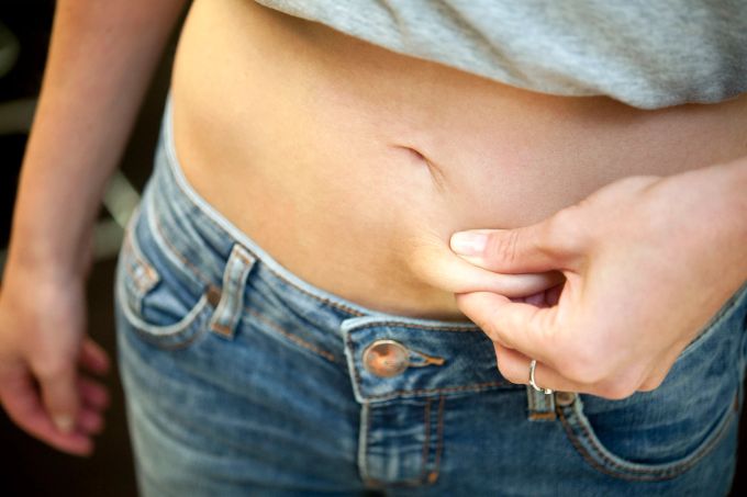 Sie sind sehr dünn, empfinden sich aber als dick: Magersüchtige haben einen verzerrten Blick auf ihren Körper. Frau Jeans Hand Bauch Fett