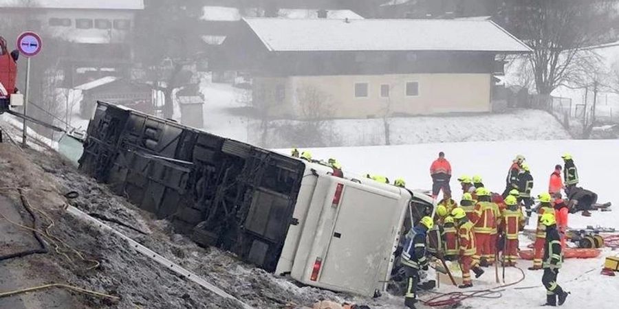 Einsatzkräfte der Feuerwehr auf der Bundesstrasse B306 am Ortsausgang von Inzell neben dem umgekippten Reisebus am Strassenrand. Foto: Kreisfeuerwehrverband Traunstein/dpa