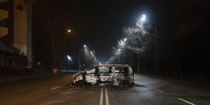 Ein verbrannter Polizeibus steht am Abend auf einer leeren Strasse in Almaty. Almaty