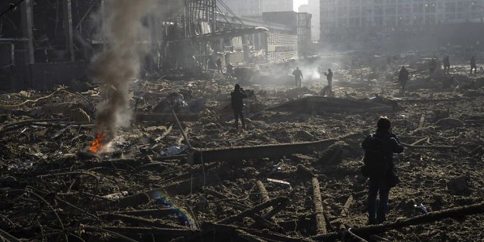 Menschen gehen durch die rauchenden Trümmer inmitten der Zerstörung, die nach dem Beschuss eines Einkaufszentrums in Kiew entstanden ist. Foto: Rodrigo Abd/AP/dpa ukraine