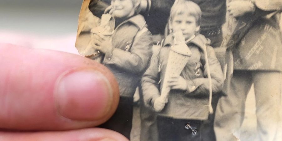 Kai Oppermann, in DDR-Kinderheimen gross geworden, zeigt ein Foto von seiner Einschulung. In der Bildmitte ist er in der vorderen Reihe mit Zuckertüte zu sehen. Links daneben steht sein Bruder Patrick.