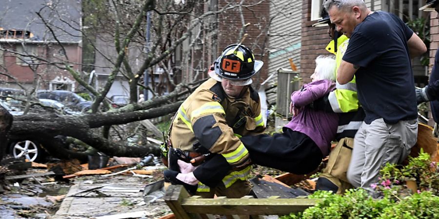 Feuerwehrleute tragen eine Frau aus ihrer Wohnung, nachdem ihr Gebäudekomplex durch einen Tornado beschädigt wurde. Foto: Stephen Swofford/Arkansas Democrat-Gazette/AP/dpa - ACHTUNG: Nur zur redaktionellen Verwendung und nur mit vollständiger Nennung des vorstehenden Credits