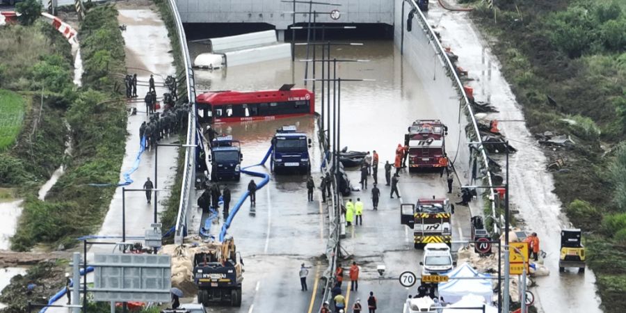 Rettungskräfte suchen nach Überlebenden auf einer Strasse, die von Fluten überschwemmt wurde und zu einem unterirdischen Tunnel führt. Foto: Kim Ju-hyung/Yonhap/AP/dpa