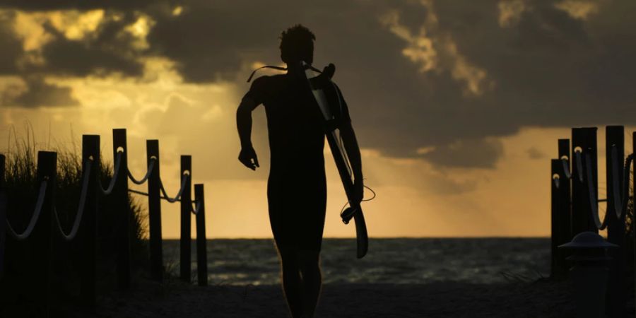 Ein Surfer geht zum Strand in Surfside im US-Bundesstaat Florida am Atlantik. (Archivbild)