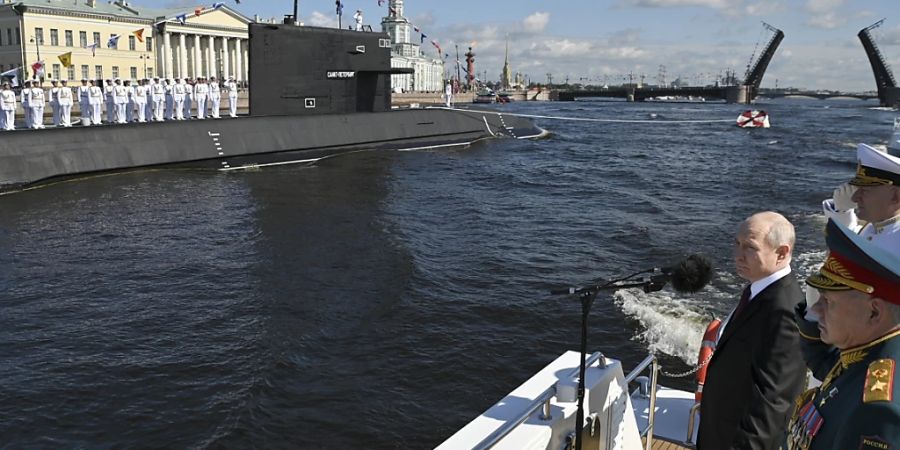 Wladimir Putin (l.) und sein Verteidigungsminister Sergej Schoigu (r.) sowie Admiral Nikolai Jewmenow (hinten) während der grossen Marineparade zum Tag der Marine in St. Petersburg. Foto: Alexander Kazakov/Sputnik Kremlin/AP/dpa