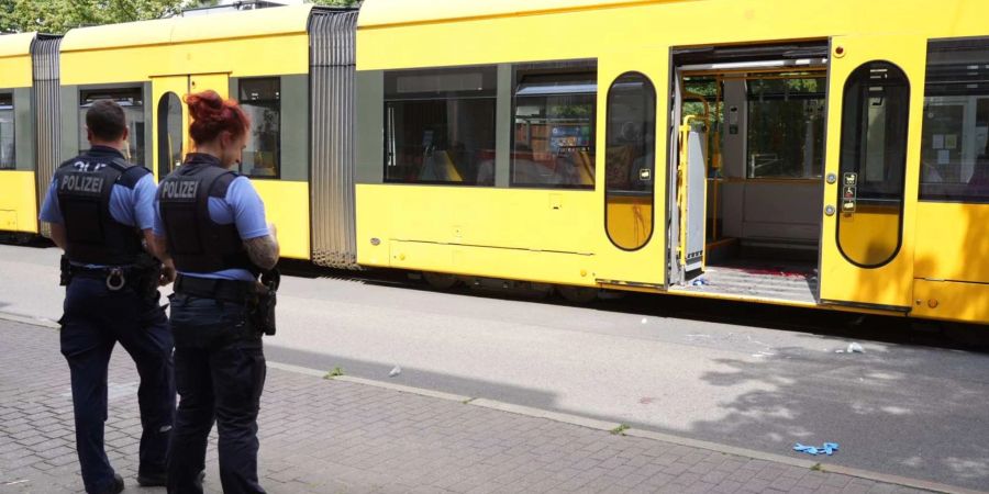 Polizisten stehen vor der Strassenbahn, in der es zu einer Messerattacke kam.