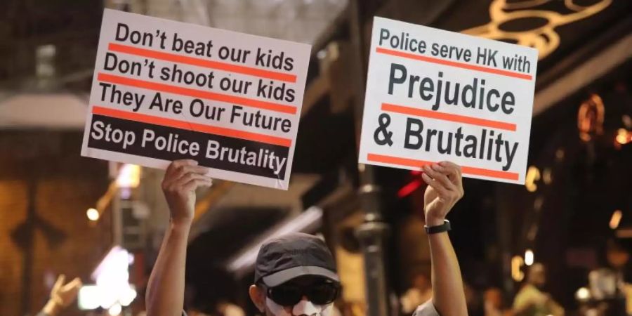 Ein Demonstrant hält Plakate bei Protesten in die Höhe. Foto: Kin Cheung/AP/dpa