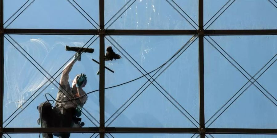 Ein spezialisierter Glas- und Gebäudereiniger putzt in 27 Metern Höhe ein Dach. Foto: Robert Michael/zb/dpa