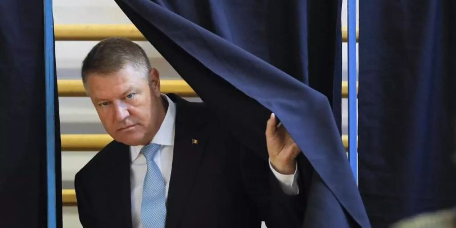 Klaus Iohannis, Präsident von Rumänien, verlässt eine Wahlkabine mit einem Stimmzettel. Foto: Vadim Ghirda/AP/dpa