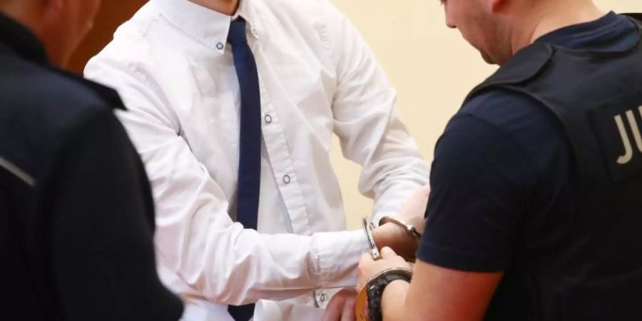 Dem Ex-Feuerwehrmann werden im Gerichtssaal in Gera die Handfesseln abgenommen. Foto: Bodo Schackow/dpa-Zentralbild/dpa