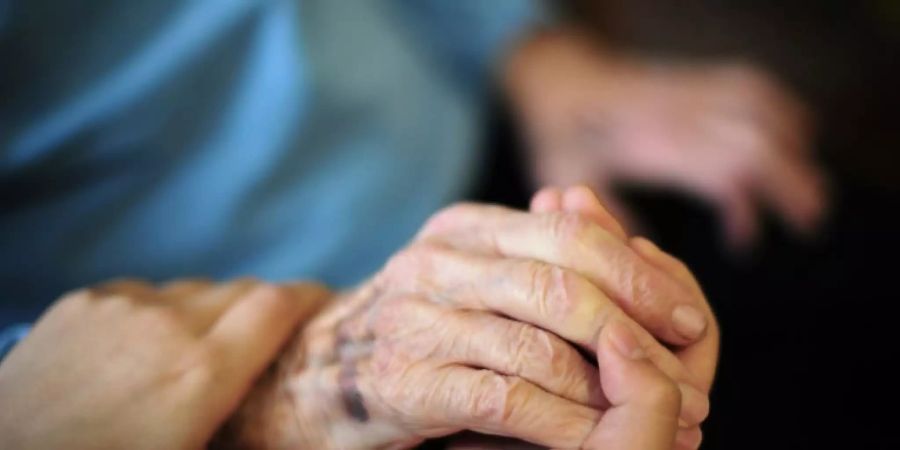 Pflegekraft hält Hand einer Heimbewohnerin