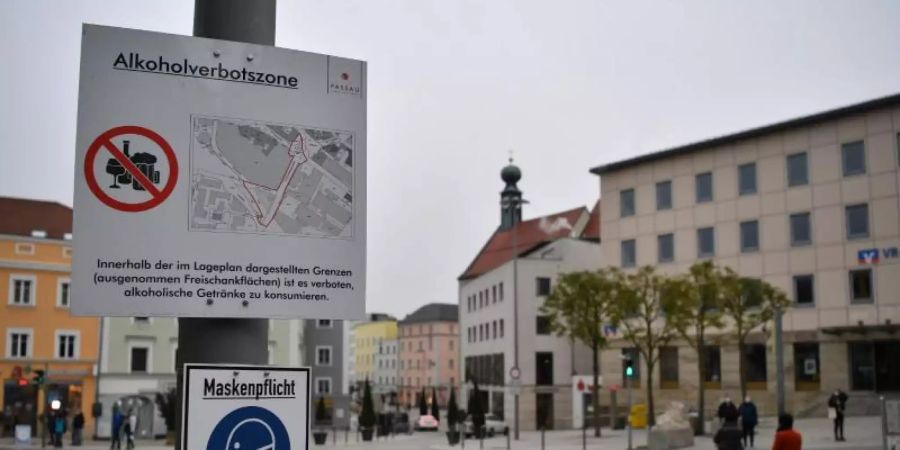 Schilder weisen am Ludwigsplatz auf die bestehende Alkoholverbotszone und die Maskenpflicht in Passau hin. Foto: Lino Mirgeler/dpa