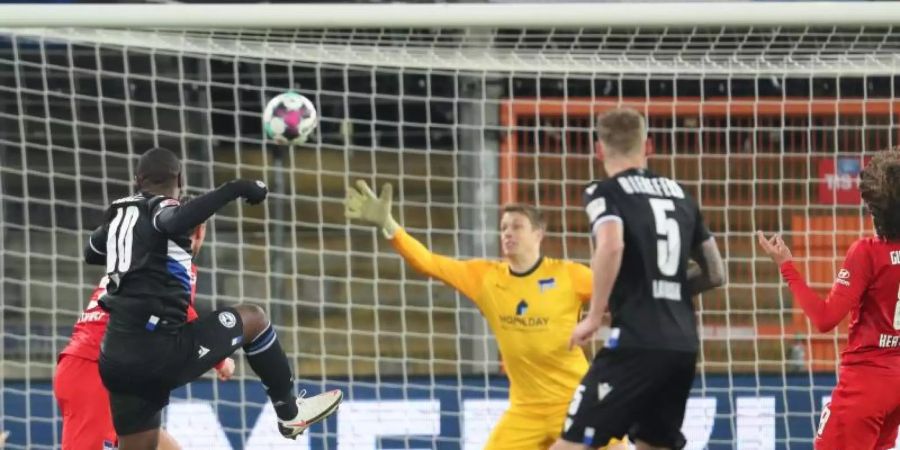 Bielefelds Reinhold Yabo (l) erzielt den Treffer zum 1:0 gegen Herthas Torwart Alexander Schwolow (M). Foto: Friso Gentsch/dpa