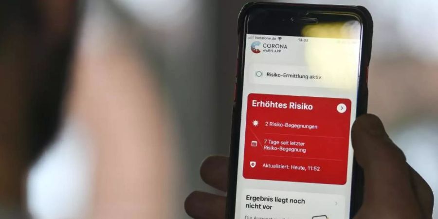 Auf einem Handy zeigt die «Corona Warn-App» ein erhöhtes Risiko an, welches darauf hinweist Kontakt mit einer infizierten Person gehabt zu haben. Foto: Kira Hofmann/dpa