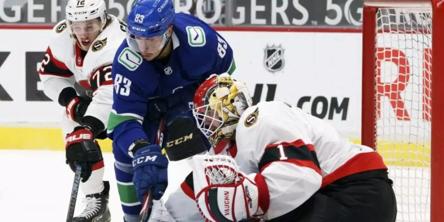 Jay Beagle (M) von den Vancouver Canucks versucht, gegen Thomas Chabot (l) und Torhüter Marcus Hogberg von den Ottawa Senators an den Puck zu kommen. Foto: Jonathan Hayward/The Canadian Press/AP/dpa